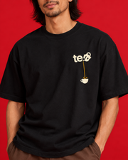 Tea Pour left chest print close-up ivory tea teapot golden stream and cup on black cotton folds